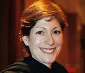 Kate Neisser, smiling in a wooden-paneled hallway