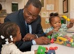 Alumnus Leon Denton with two young girls at a Salvation Army child care center