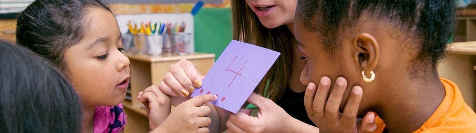 Female math teacher showing female students early childhood math concepts.