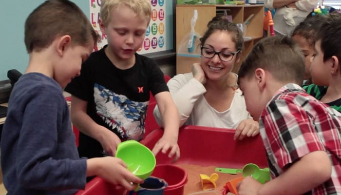 Female teacher with students learning math through play.