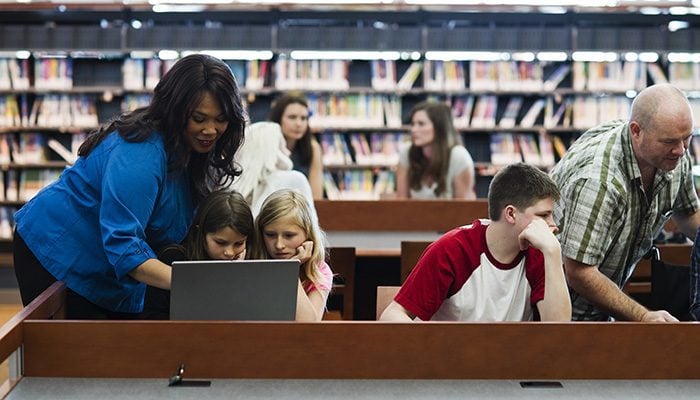 Stock photo of a group of people using technology in a library.