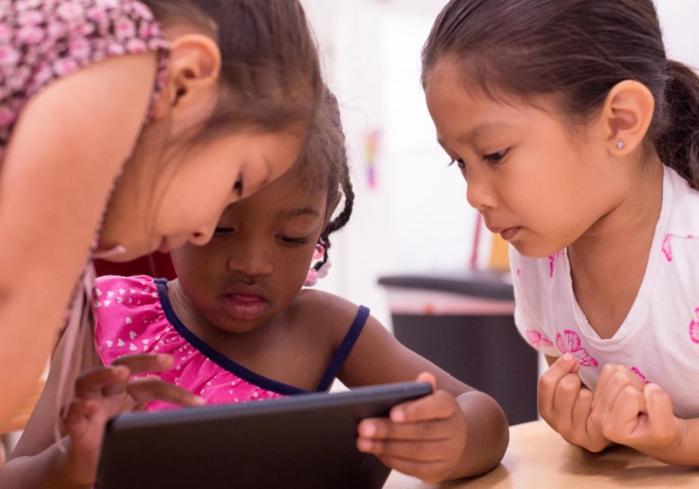 group of 3 students gathering around an ipad