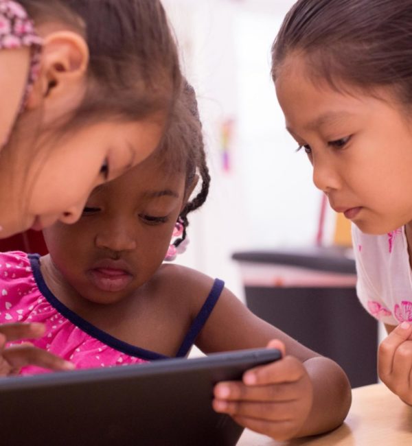 group of 3 students gathering around an ipad