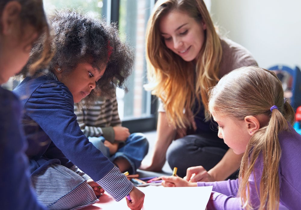 Social worker with young children drawing together.