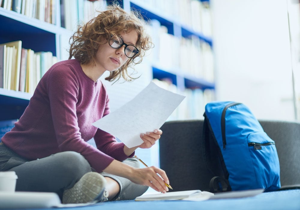 Concentrating student sitting on the floor working on university research.