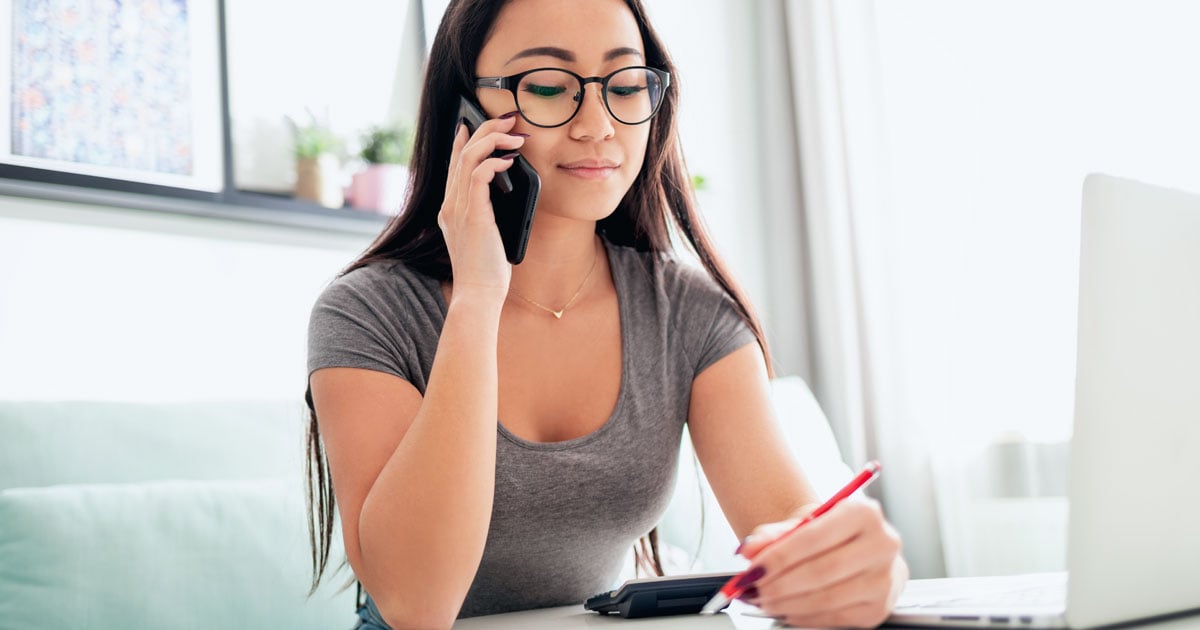 Woman seated at a desk talking on a smartphone.