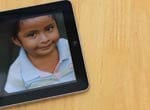 Photo of child on an iPad sitting on a wooden table