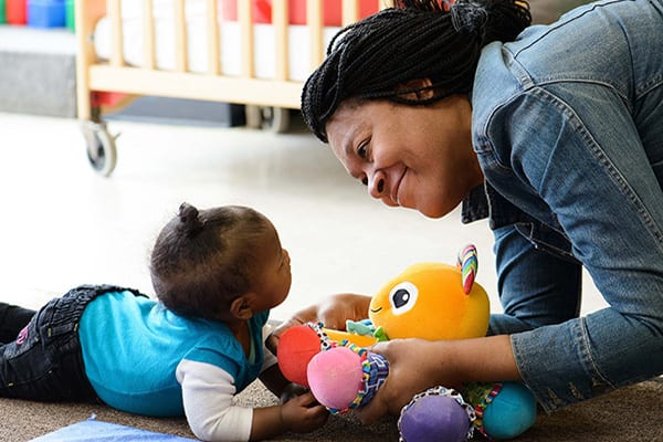 Woman playing with a baby on the floor.