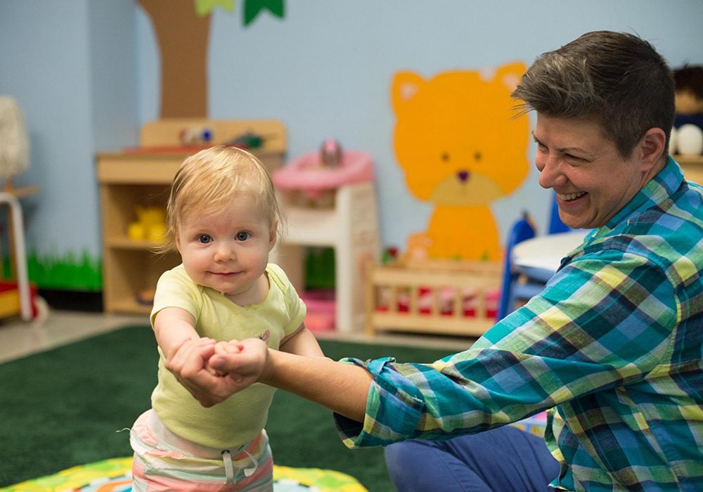 A pediatric mental health specialist smiling at a toddler.
