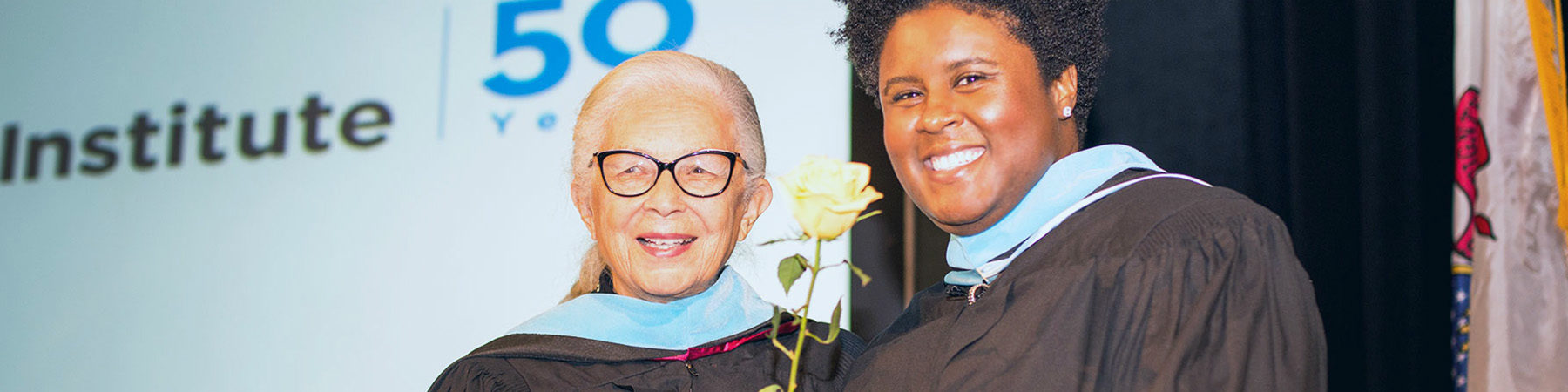 Two students in caps and gowns graduating.