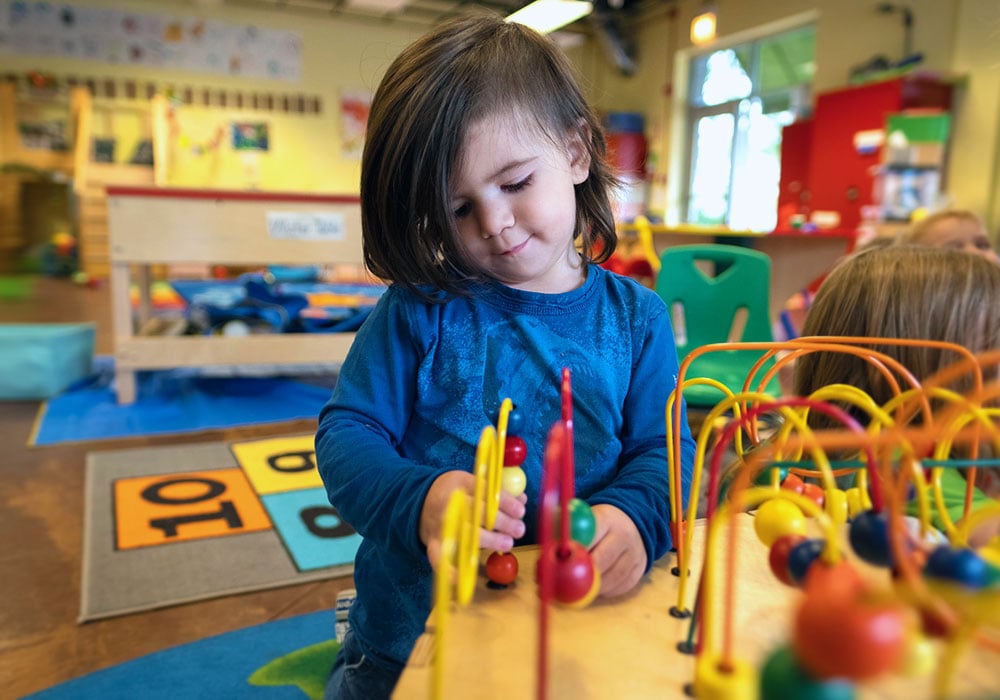 Preschooler playing with educational toys in a classroom.