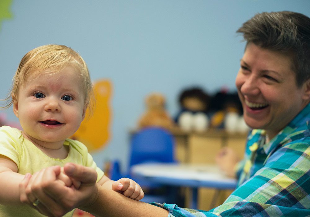 Infant Mental Health Specialist holding a standing toddler.