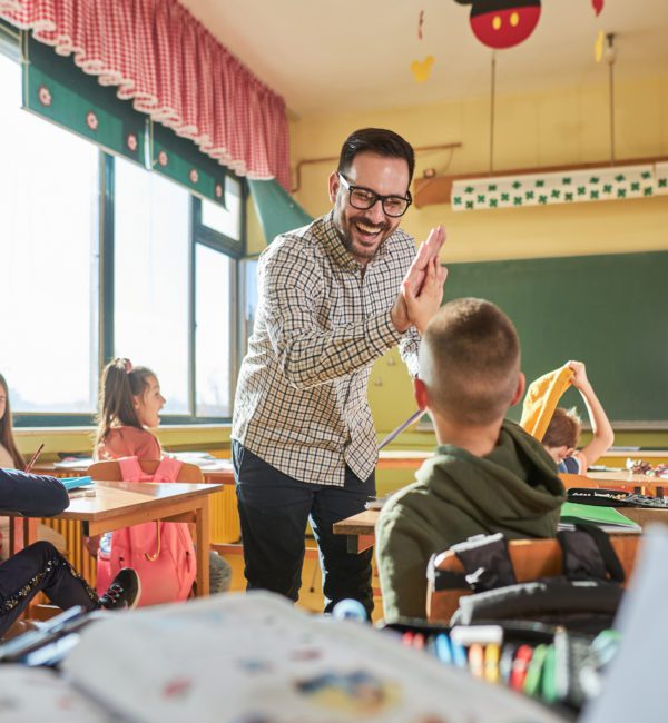 Happy teacher and schoolboy giving each other high-five on a class.