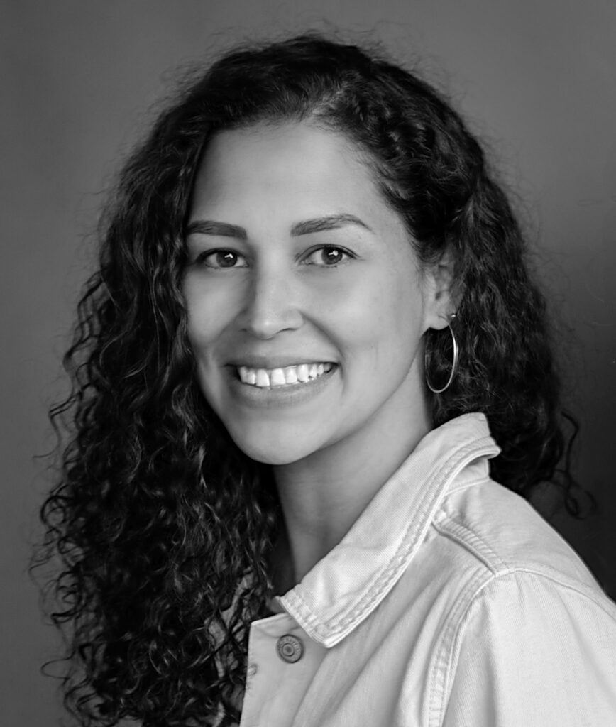 black and white portrait of woman with long curly hair wearing a white shirt smiling
