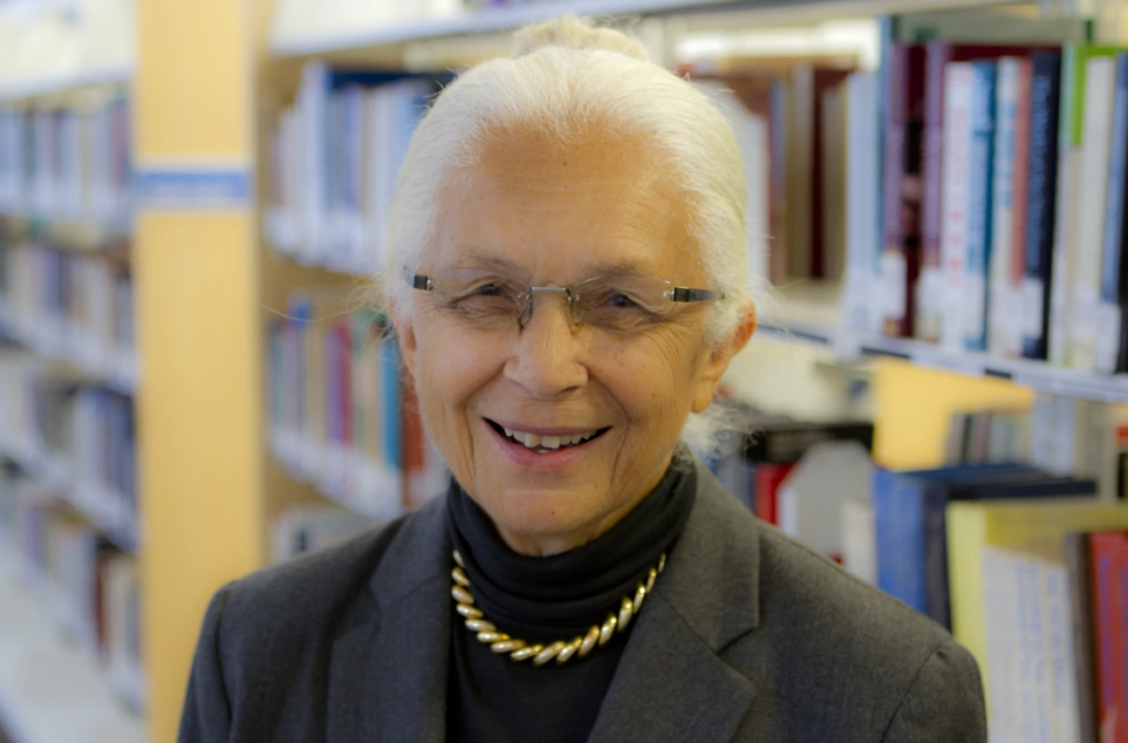 older woman with eyeglasses wearing a black turtle neck and grey blazer