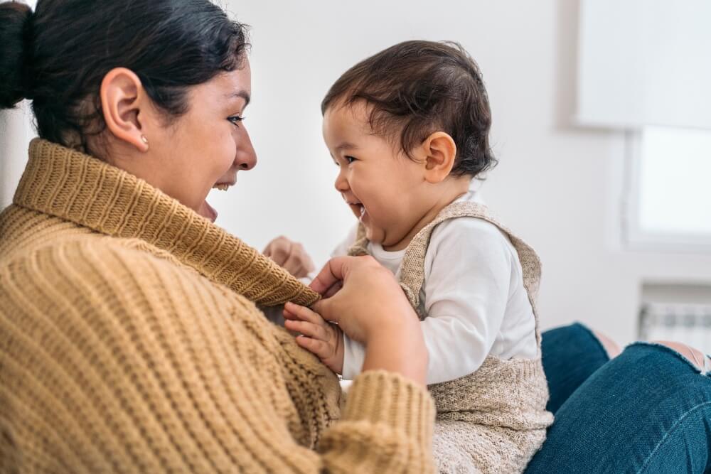 An adult responds to a baby's reach, making eye contact during a moment of back-and-forth connection