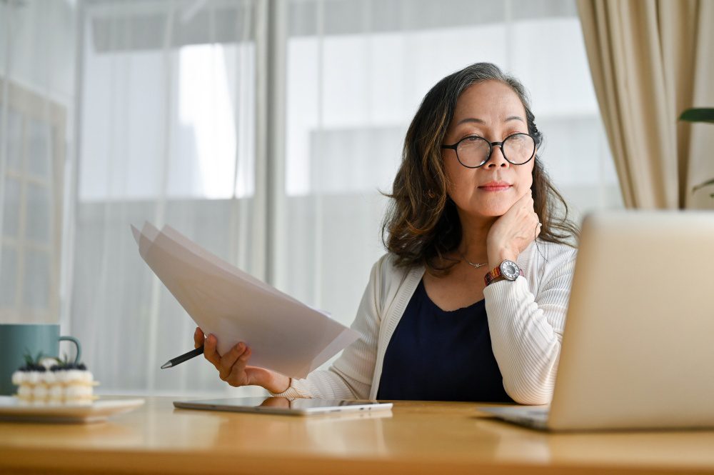 working professional at a home desk with a laptop and documents, calm and focused