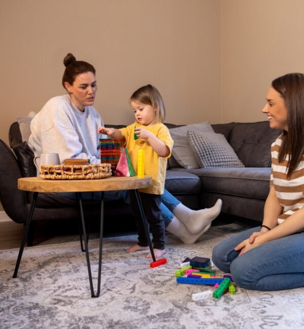 A practitioner sitting at child level with a toddler during a home visit