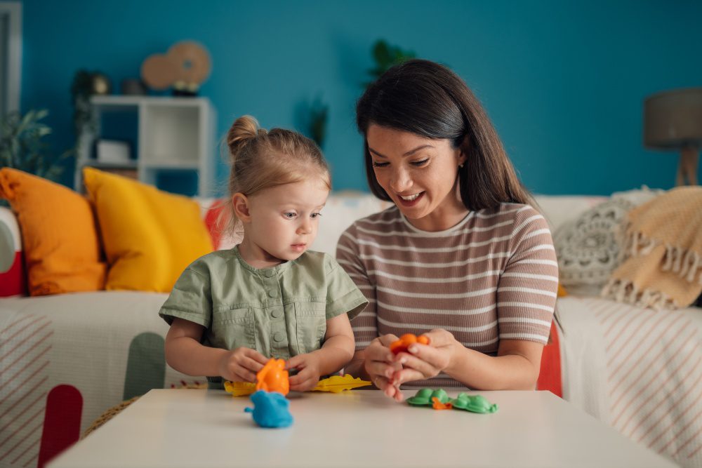 toddler and parent at a table with play dough, hands in frame