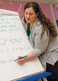 Photo of Pryor teaching math by writing on a whiteboard in Spanish